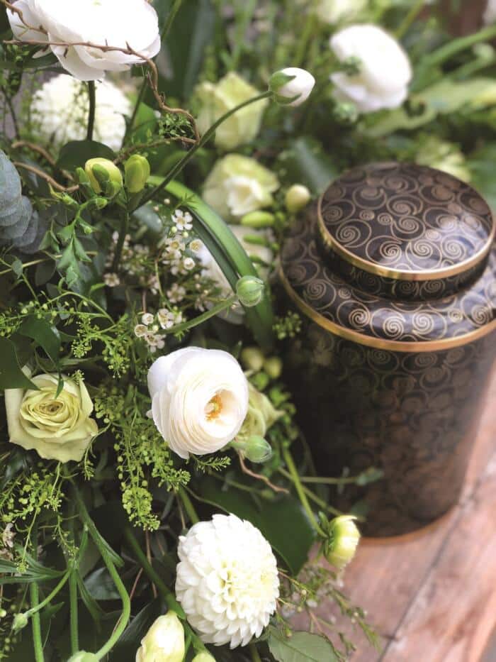 The Watering Can | White rununculus and dahlias alongside a variety of greenery in a floral cremation design.