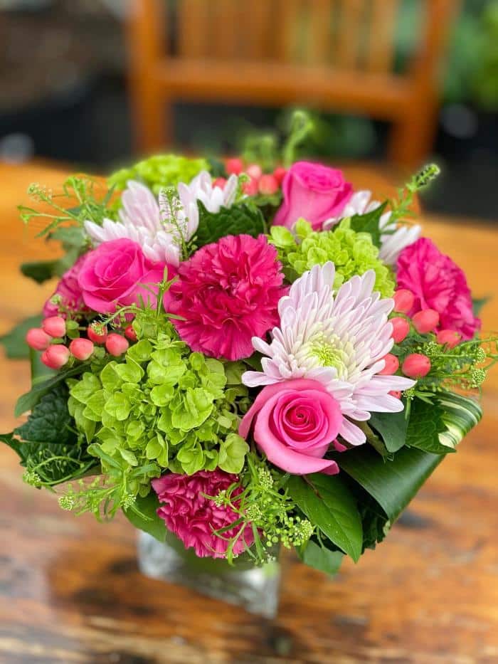 The Watering Can | A compact hot pink and bright green bouquet in a square glass vase.