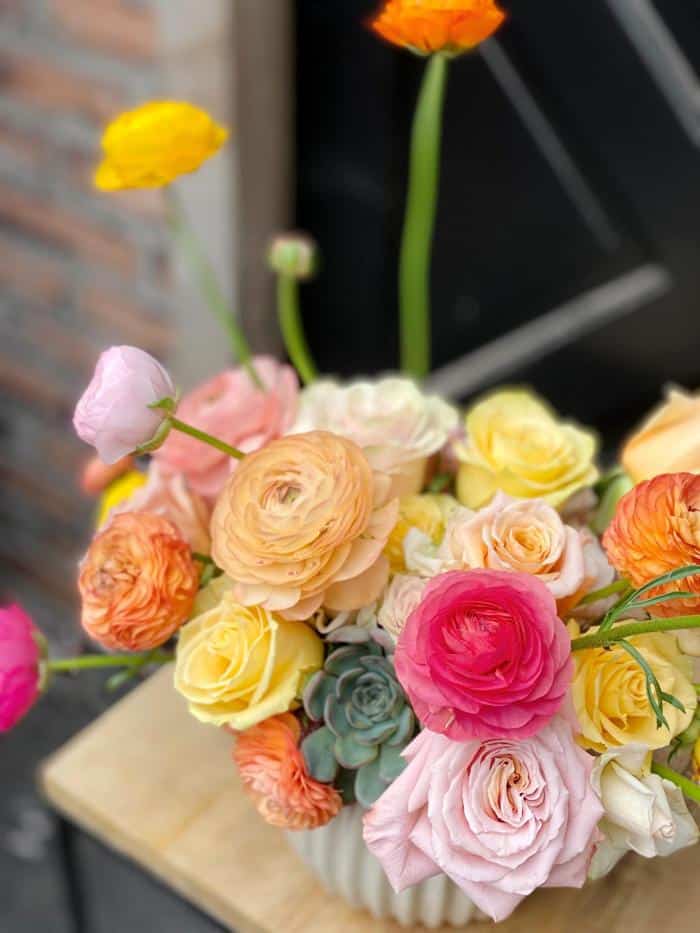 The Watering Can | Close up of the colourful roses and ranunculus used in this whimsical European Arrangement.
