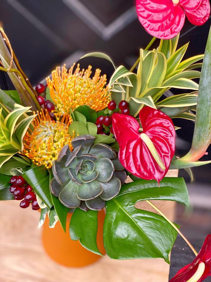 The Watering Can | A close up from above of the anthurium, pincushion and tropical greenery used in a compact European style arrangement.