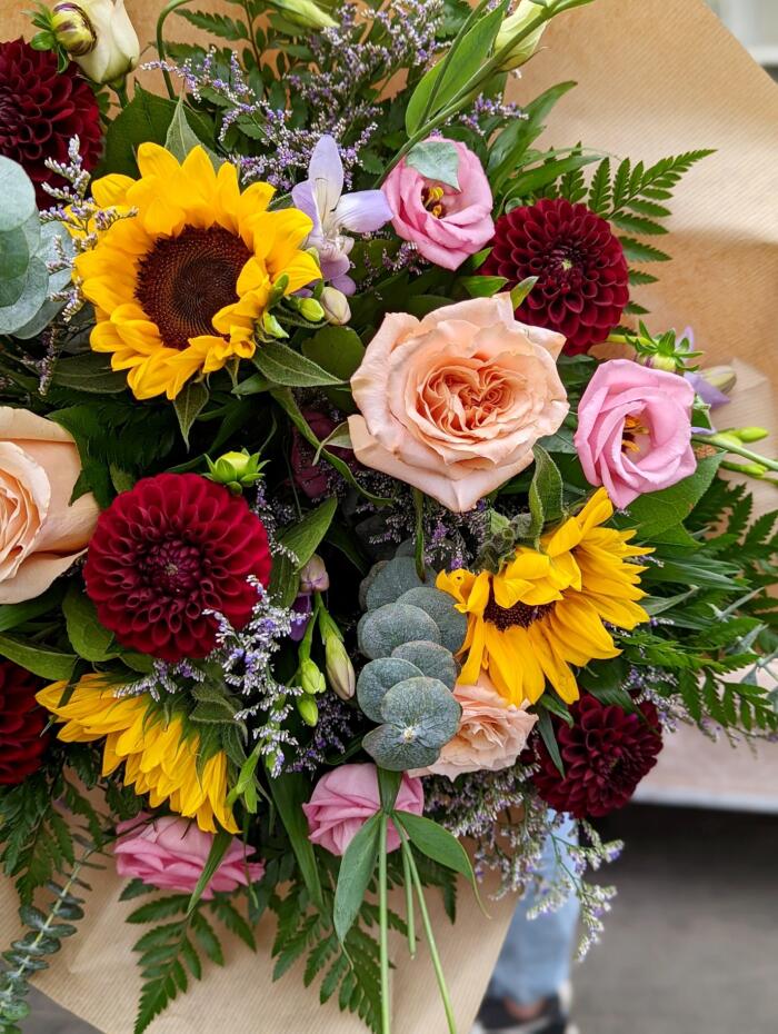 The Watering Can | Close up of the roses, lisianthus, dahlias, and sunflowers in a hand-tied bouquet.
