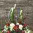 The Watering Can | White, red, and burgundy flowers and greens arranged all around an urn.