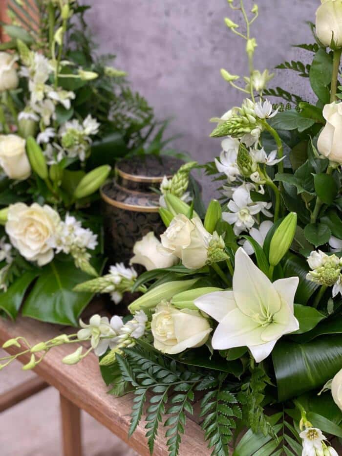 The Watering Can | White roses, lilies, Star of Bethlehem, and dendrobium orchids in a floral cremation design.