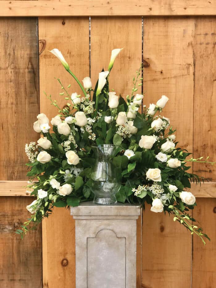 The Watering Can | A large spary of white flowers behind a cremation urn on a plinth.