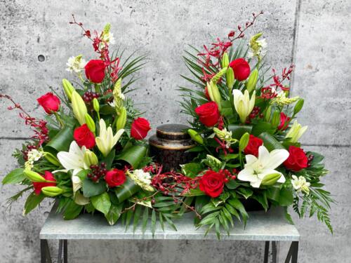 The Watering Can | An elegant cremation display that rises up on either side of the urn made with red roses, white lilies, star of bethlehem, gurgundy hypericum and anabelle orchids.