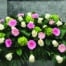 The Watering Can | A casket spray made with white roses, green hydrangea, and pink and white gerbera daisies in a lush bed of greens.
