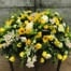The Watering Can | A yellow casket spray made with white cymbidium orchid, bright yellow roses, white peonies, bright yellow gerberas, white dendrobium orchids, stars of Bethlehem, yellow freesia, green hypericum, and white trachelium on a bed of greens.