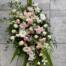 The Watering Can | A blush and white easel spray made with white roses, blush rununculus,soft pink spray roses, white dendrobium orchids, pink veronica, white cymbidium orchids, white gerberas, and white hypericum on a bed of greens.