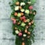 The Watering Can | A coral and white easel spray made with coral roses, white mums, peach/coral dahlias, white peonies, peach gerberas, and white hypericum.