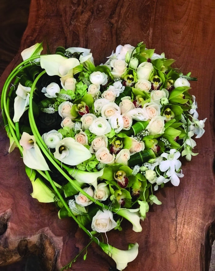 The Watering Can | A modern heart design using a variety of white flowers with long calla lilies along one side.