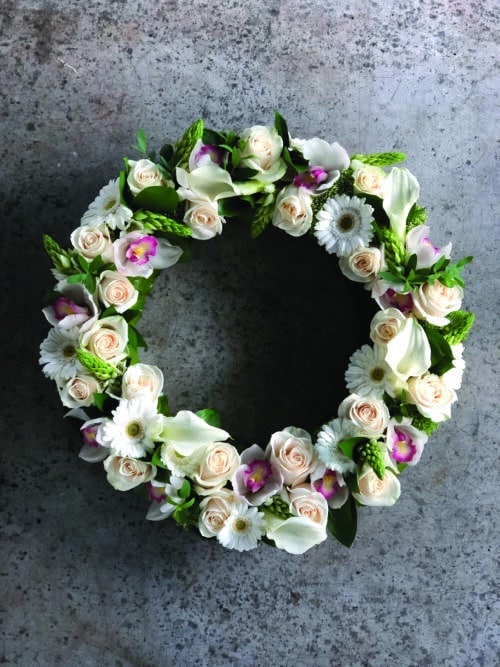 the Watering Can | A gorgeous white and soft pink flowered wreath with roses, cymbidium orchid blooms, calla lilies, gerbera daisies, and star of Bethlehem.