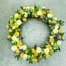The Watering Can | A large yellow, white, and purple floral wreath.