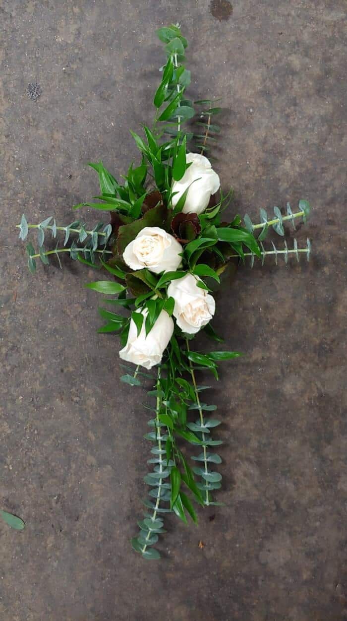 The Watering Can | Baby blue eucalyptus and ruscus in the shape of a cross with four white roses.