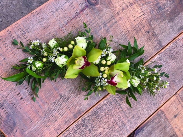 The Watering Can | A small garland of ruscus, white hypericum, white spray roses, and green cymbidium orchids.