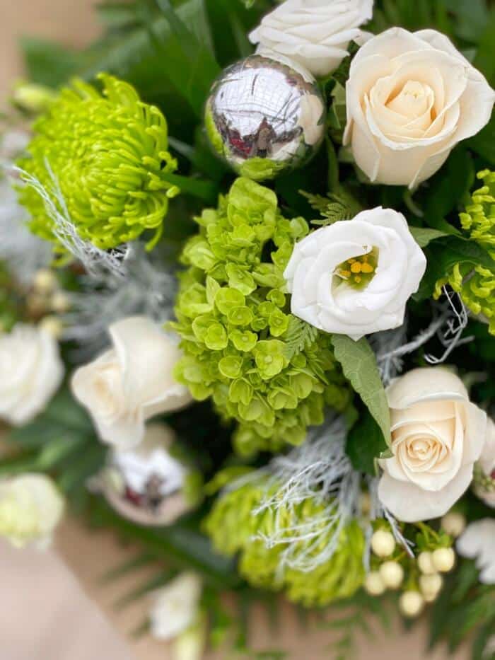 The Watering Can | Close up image of green hydrangea, white lisianthus, and white roses in a hand-tied bouquet.