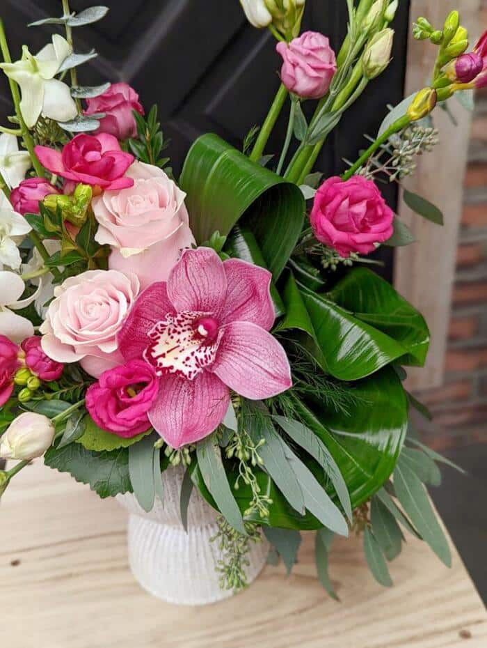 The Watering Can | Close up of the pink cymbidium orchids, roses and lisianthus in a Europen style floral arrangement,
