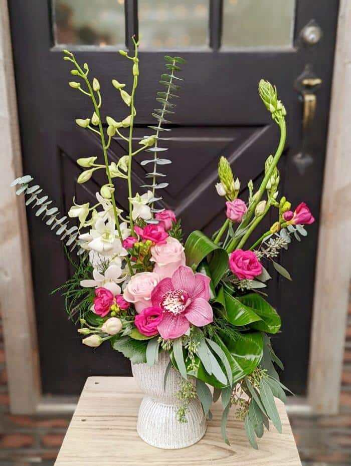 The Watering Can | A tall pink European style floral arrangement in a white ceramic pedestal vase.