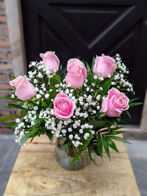 an iridescent vase with 1/2 dozen rose bouquet with babys breath and greenery