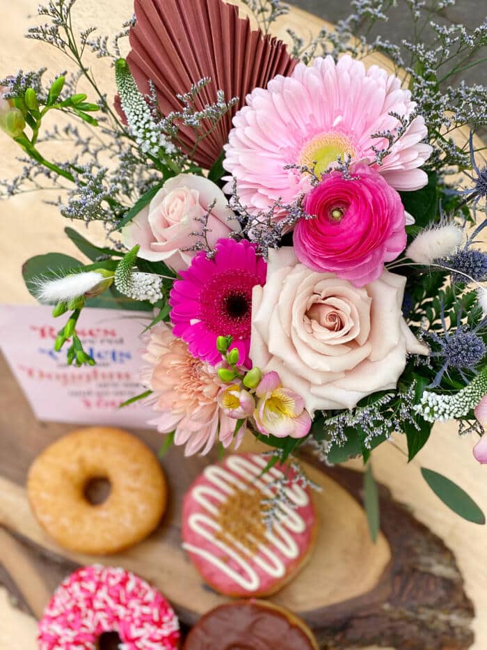 The Watering Can | View from above of a pink bouquet and 4 doughnuts.