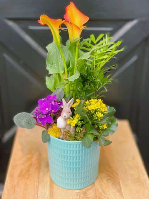The Watering Can | A cheerful spring planter in a turquoise blue pot with a small bunny figurine.
