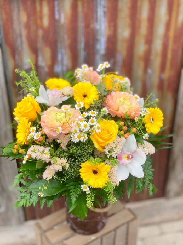 The Watering Can | A large blush and yellow bouquet in a burgundy glass vase.