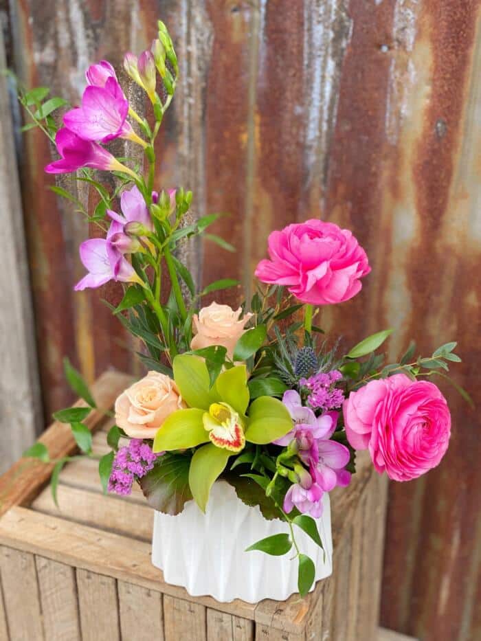 The Watering Can | A pink and purple European style floral arrangement in an oval white geometric container.