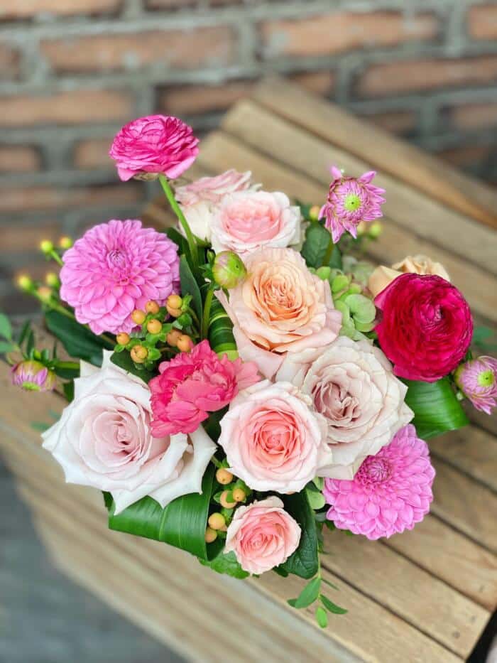 The Watering Can | View from above of a low European style floral arrangement made with pink roses, ranunculus, and dahlias.