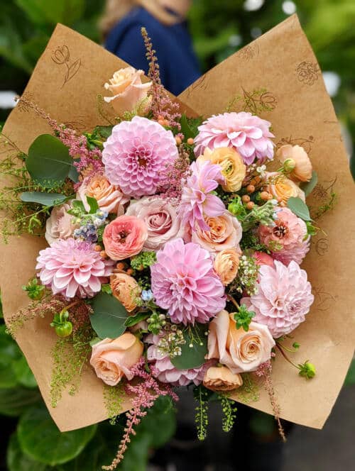 The Watering Can | A generous blush and peach handtied bouquet with lots of dahlias, roses, and ranunculus.