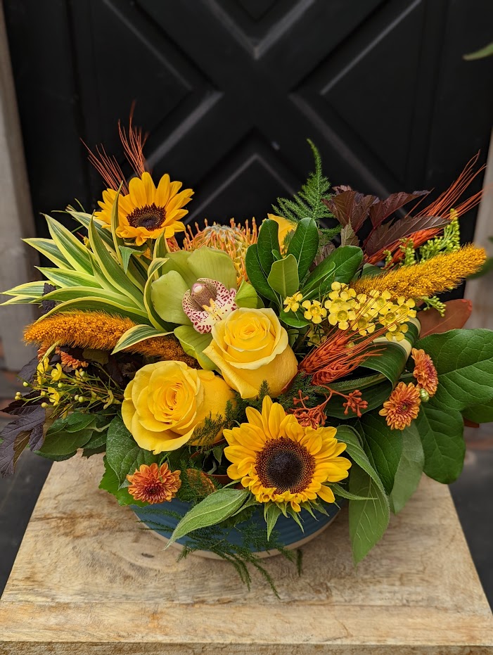 The Watering Can | An European style arrangement of yellow blooms in a low round blue ceramic container.