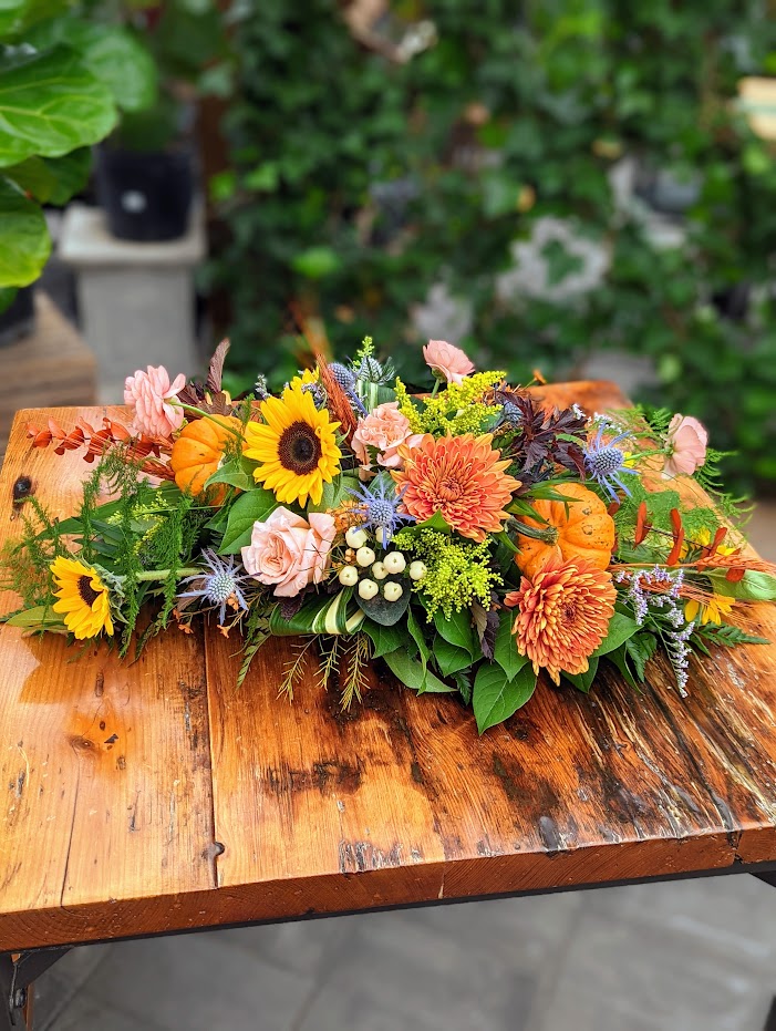 The Watering Can | An oblong fall themed table centerpiece with yellow, orange, and burgundy.