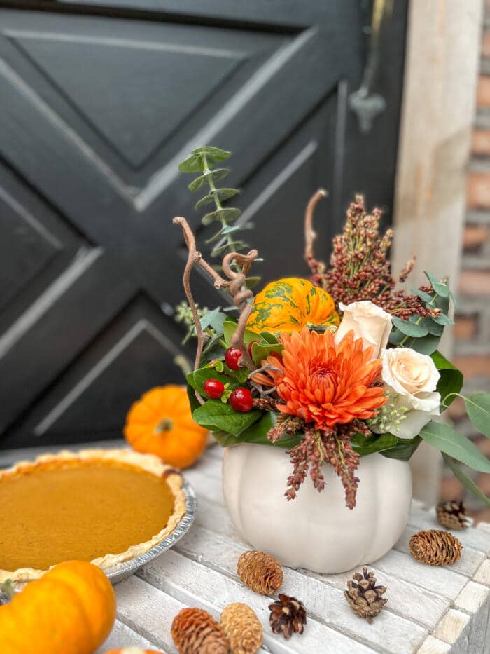 The Watering Can | A fall European style arrangement in a ceramic white pumpkin shaped container beside a pumpkin pie.