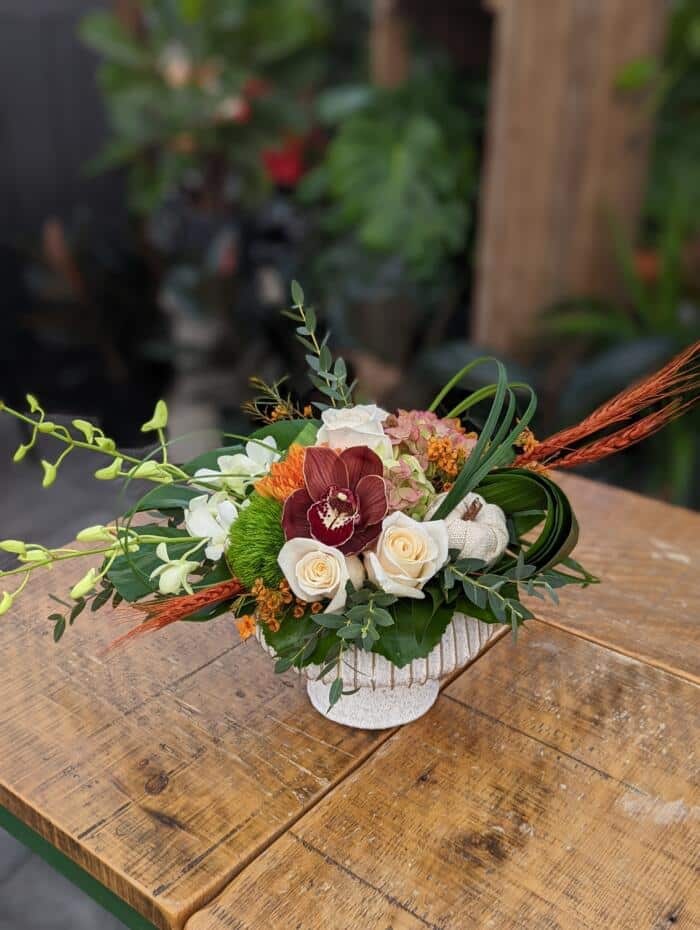 The Watering Can | A deep burgundy, orange, and white European style arrangement.