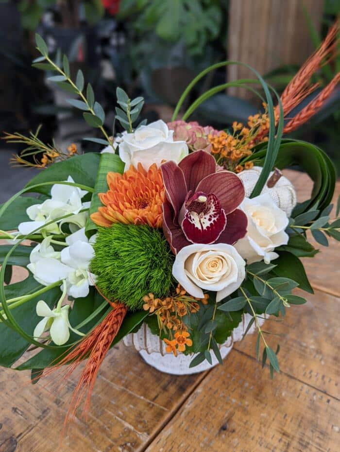 The Watering Can | Alternate view of a deep burgundy, orange, and white European style arrangement.