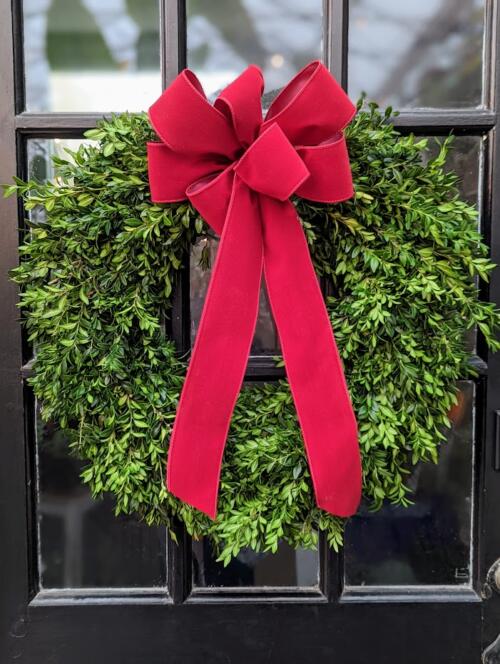 The Watering Can | A wreath made entirely from boxwood with a red bow.