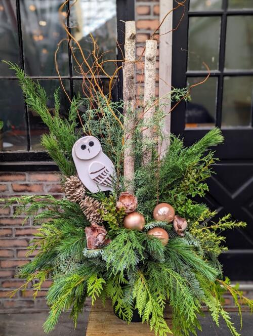 The Watering Can | An outdoor winter design with two birch poles, a large wooden owl and natural ornaments and decorations.