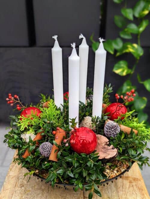 The Watering Can | Four white candles in a festive arrangement with red ornaments designed in a glass bowl.