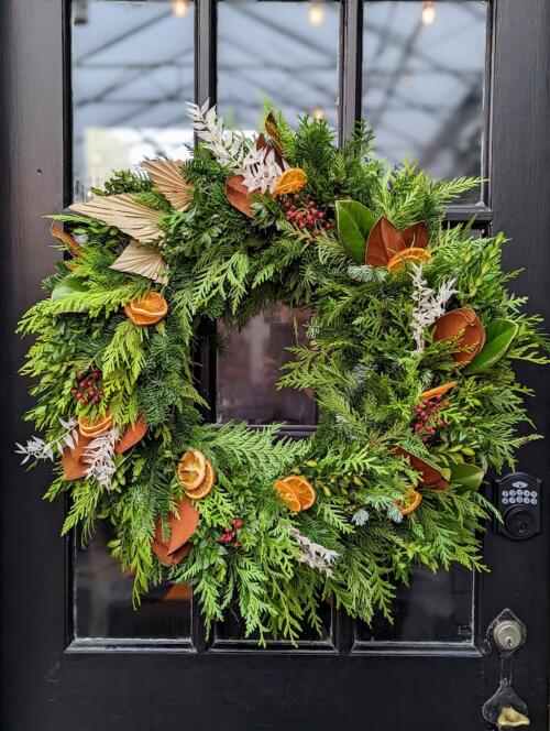 The Watering Can | A winter wreath with magnolia, orange slices, rosehips, dried ruscus, and curly willow.