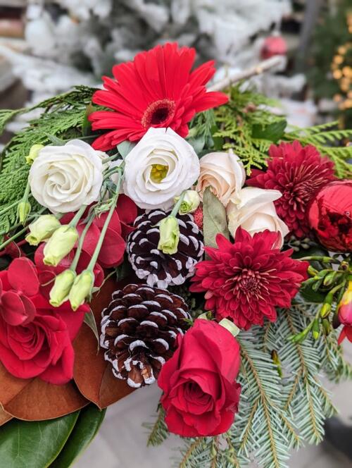 The Watering Can | A selection of loose red and white flowers and pinecones with winter greens.