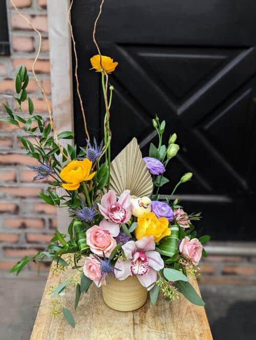 The Watering Can | An European style arrangement in pink, lavender, and yellow designed in a pale yellow ceramic container.