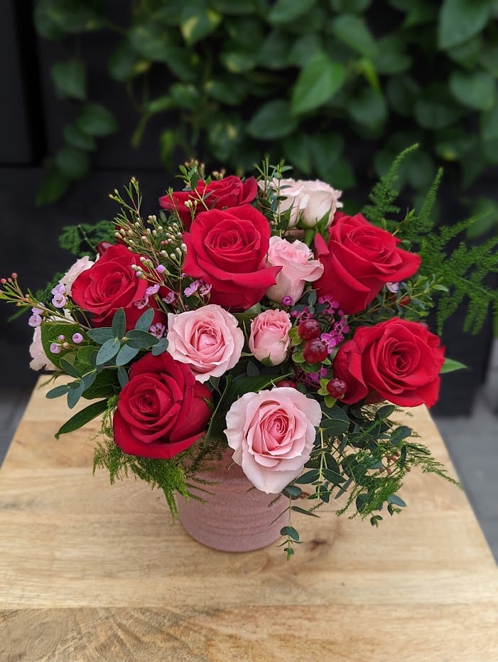 The Watering Can | A bouquet of pink and red roses in a pink ceramic vase.
