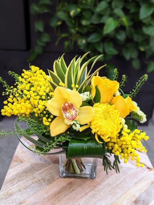 The Watering Can | An all yellow bouquet in a square glass vase.