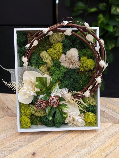 The Watering Can | A moss art design featuring a wreath hoop decorated with dried white florals in a white frame.