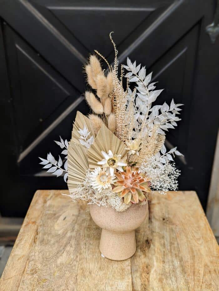 Beige ceramic tiered container. Featuring a variety of beige and white dried florals.