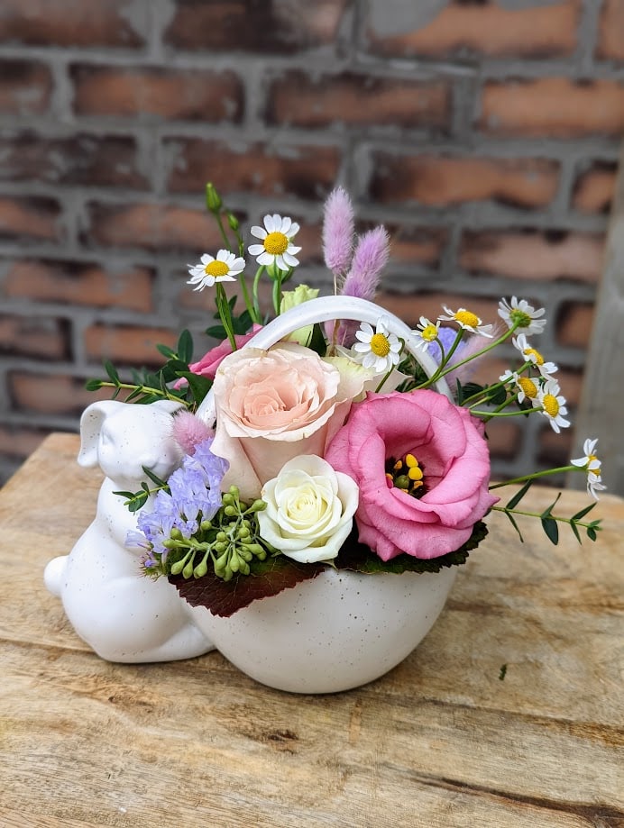 A white ceramic bunny container filled with pastel coloured flowers. Sprigs of dainty white and yellow chamomile and a mix of green eucalyptus. The perfect size for a centrepiece or a gift this spring.