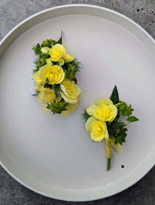 A bright yellow corsage and boutonniere on a white tray.