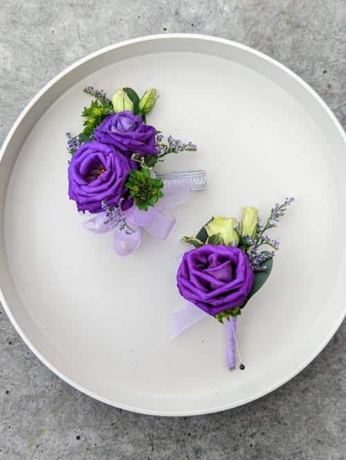 Tray with bright purple lisianthus corsage and boutonniere. Hints of light purple limonium and green bluperum with a purple ribbon.