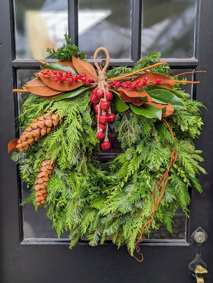 A 16 inch cedar wreath accented with red bells, pincecones and magnolia