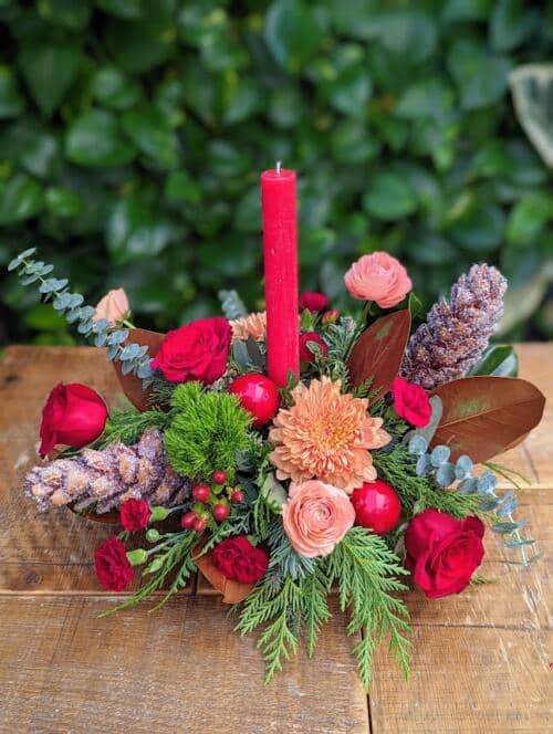 winter greens with peach mums, peach ranunculus, red roses, burgundy carnations and more.