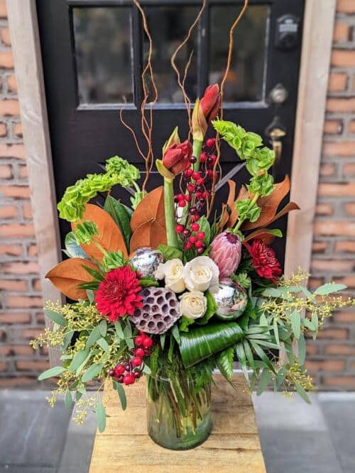 A large overflowing holiday bouquet, featuring bells of ireland, magnolia, roses, protea ad more