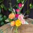 small glass vase featuring pink lisianthus, pink spray roses, peach ranunculus, purple tulips thistle and more.